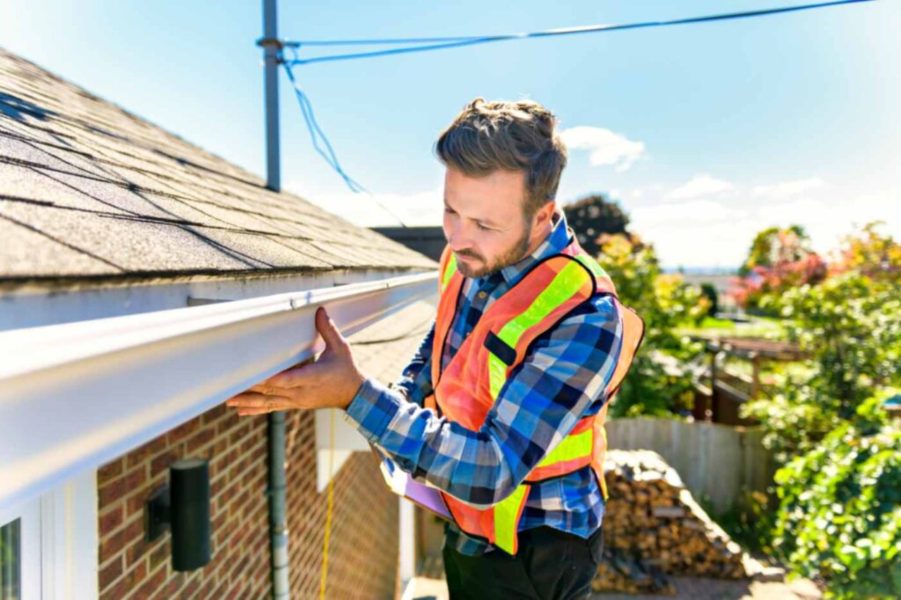 a man standing on steps inspecting house roof